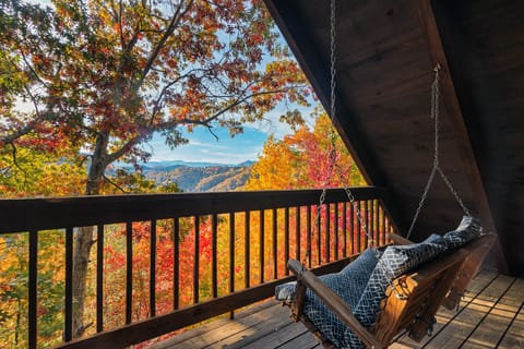 Porch swing on a covered deck overlooking fall foliage and mountain ridges