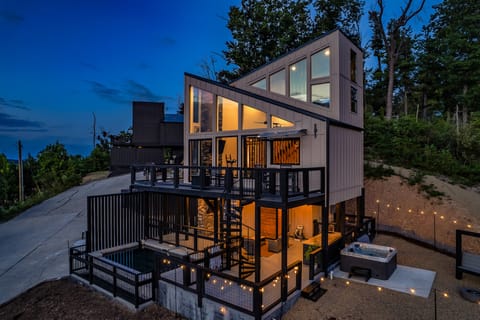 Modern multi-level cabin exterior at twilight with a private pool and string lights