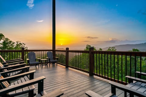 Wraparound deck with adirondack chairs overlooking a mountain sunrise