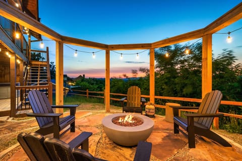 Fire pit patio with adirondack chairs and string lights at dusk, mountain view